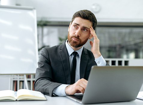 Tired businessman at desk, experiencing leaky gut symptoms