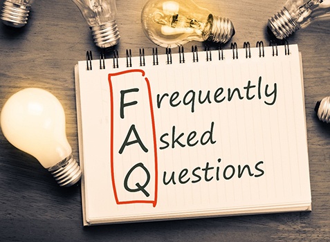 Frequently asked questions notepad next to lightbulbs on tabletop