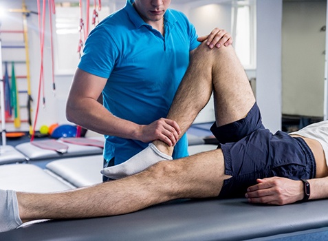 Doctor manipulating patient’s leg during muscle energy treatment