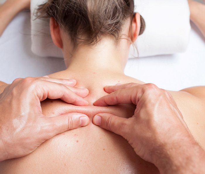 Pair of hands massaging patient’s back during myofascial release in Saint Cloud