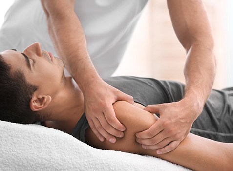 Hands massaging male patient’s arm during myofascial release session