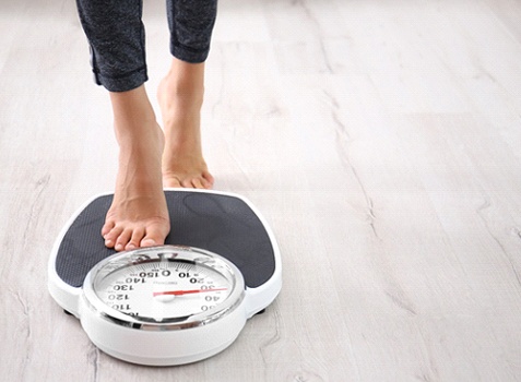 Person stepping on scale after wellness counseling via telemedicine