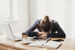 Stressed woman at desk, suffering from adrenal fatigue